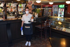 A bar area with a bartender, shelves of liquor, and a refrigerator with a Coca-Cola logo.