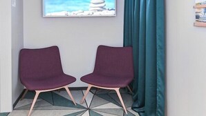 A hotel room with a bed, a TV mounted on the wall, and a window with curtains. - Hotel Fridhem (Stockholm)