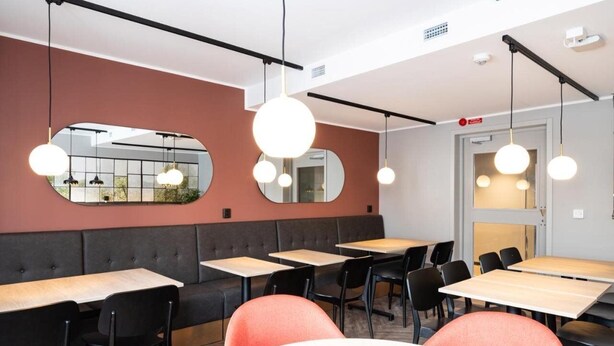 A modern dining area with round tables, black chairs, and pendant lighting. - Hotel Fridhem (Stockholm)