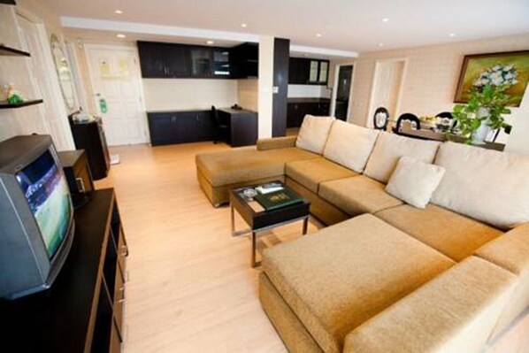 A modern living room with a sectional sofa, a coffee table, and a television. - Roseate Ratchada (Bangkok)