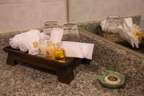 Un plateau en bois contenant des articles de toilette, notamment du gel douche, un après-shampoing et un shampoing, ainsi qu’un porte-savon avec un pain de savon.