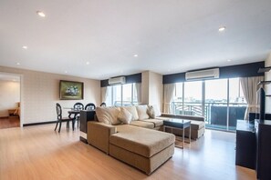 Relax in this stylish living room with a large sofa, dining area, and city view.