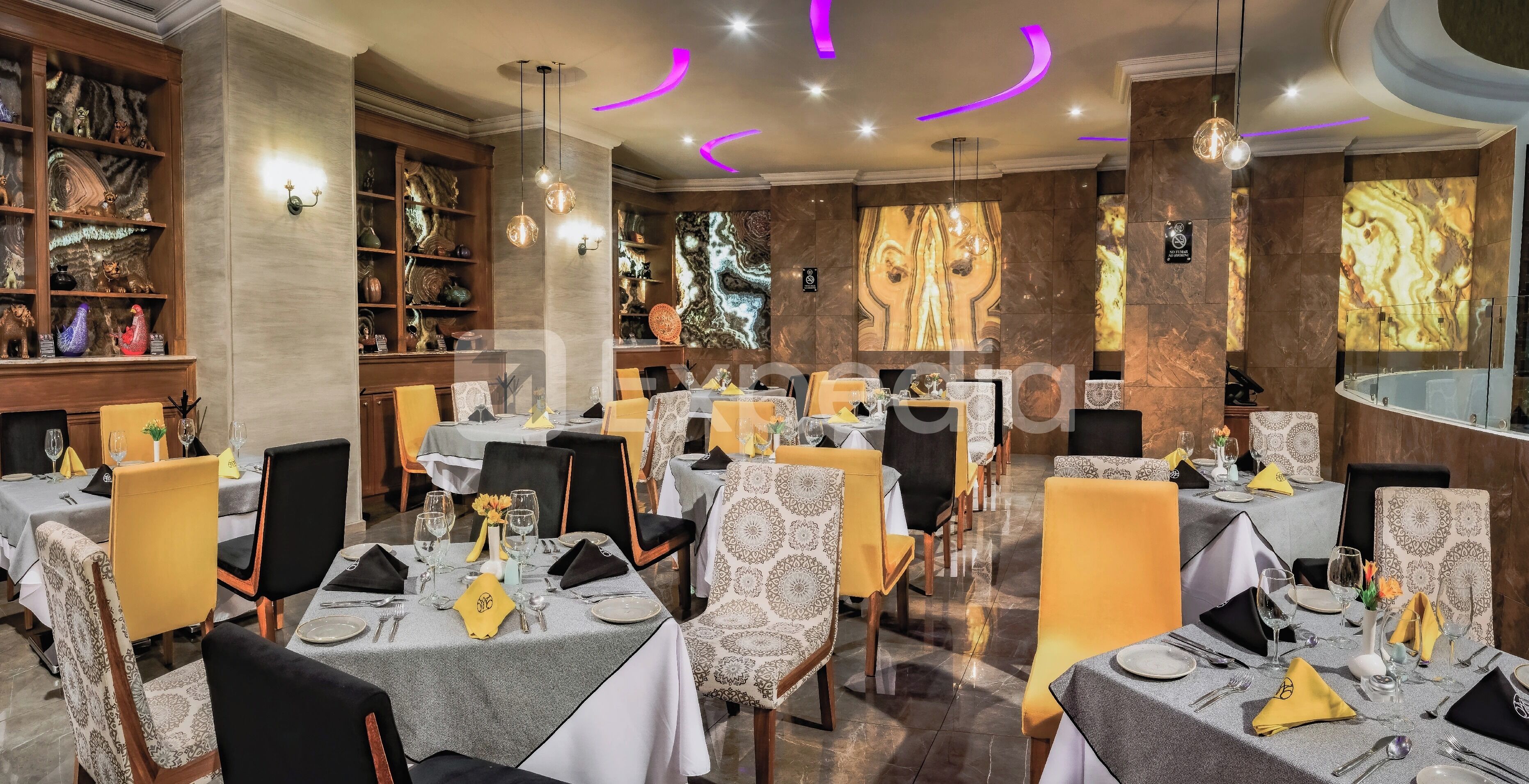 Un restaurante con varias mesas dispuestas para comer, con manteles estampados y sillas.