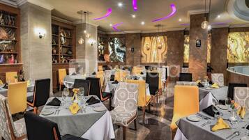 Un restaurante con varias mesas dispuestas para comer, con manteles estampados y sillas.