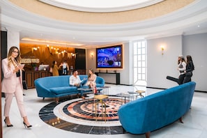 Un hall d’entrée avec un canapé bleu, une table basse ronde et un écran de télévision.