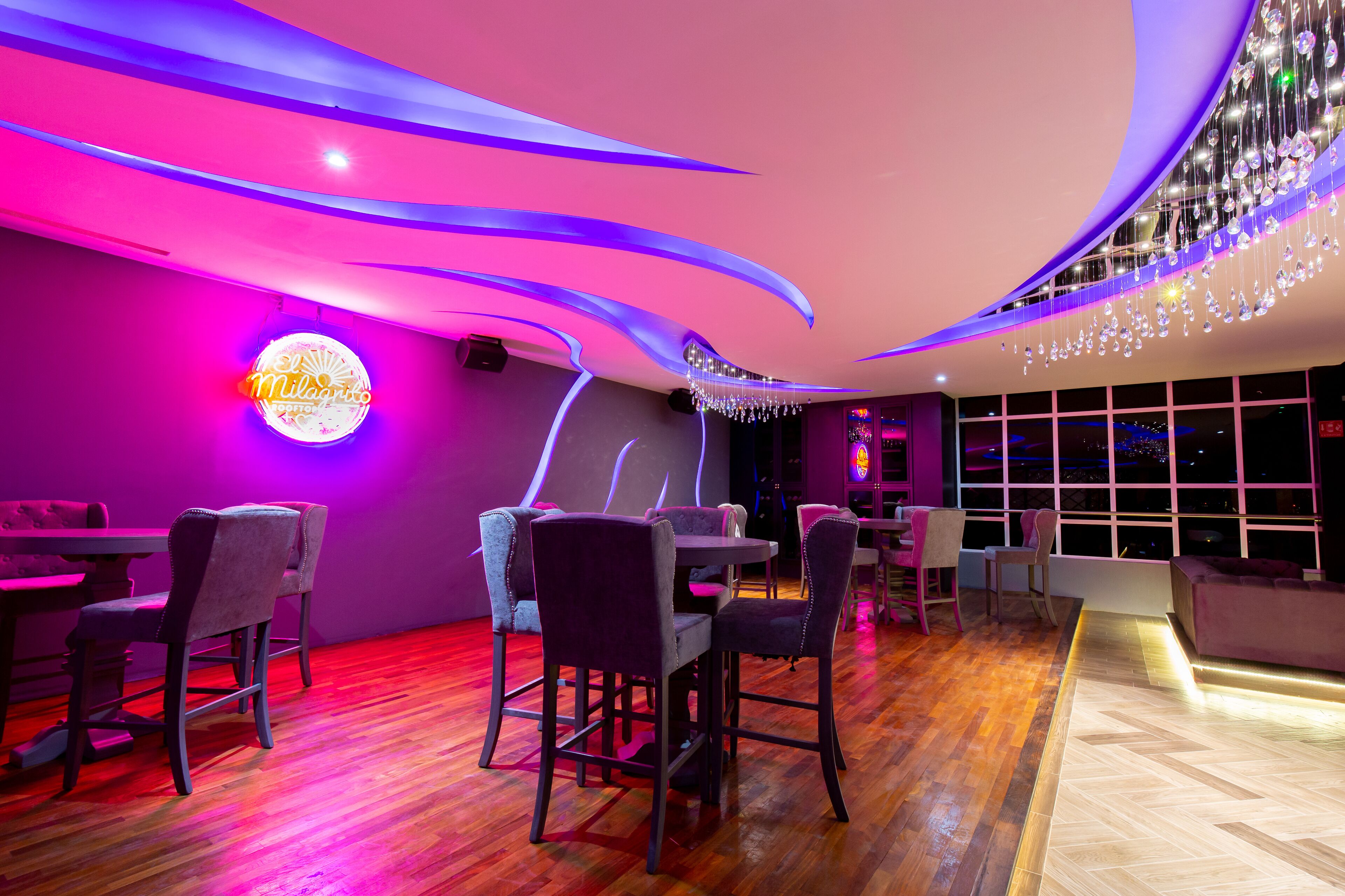 A restaurant with a modern interior, featuring purple lighting and a neon sign.