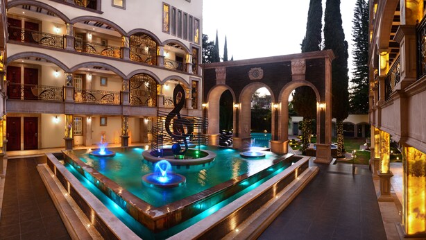 Un patio de hotel lujoso con una fuente central, varios balcones y arquitectura clásica.