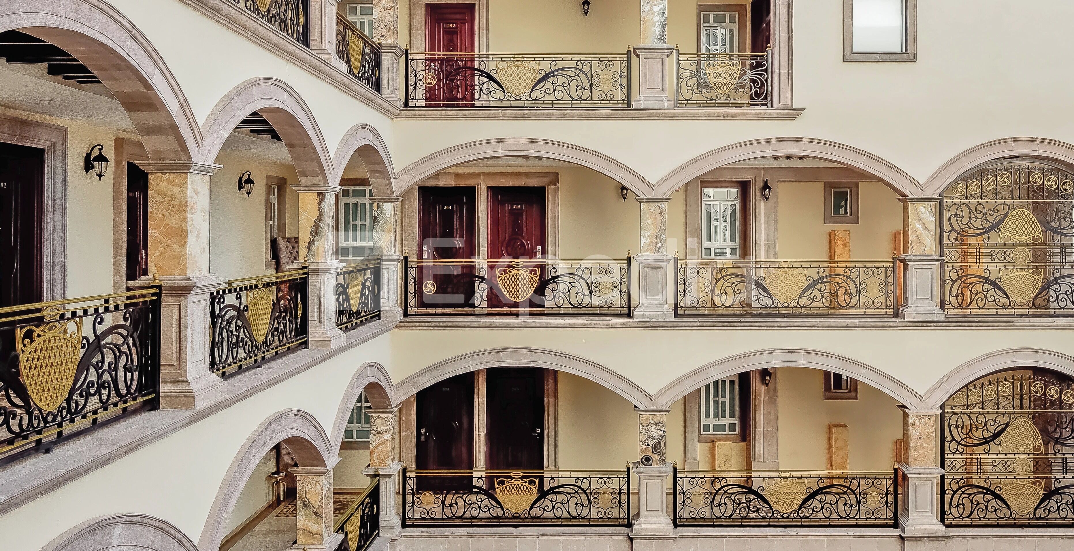 A multi-level building with balconies, arched doorways, and decorative iron railings.
