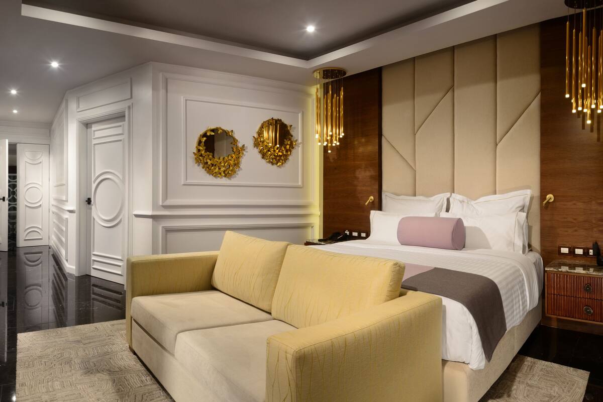 Un dormitorio moderno con cama, sofá, televisión y un adornado en la pared.
