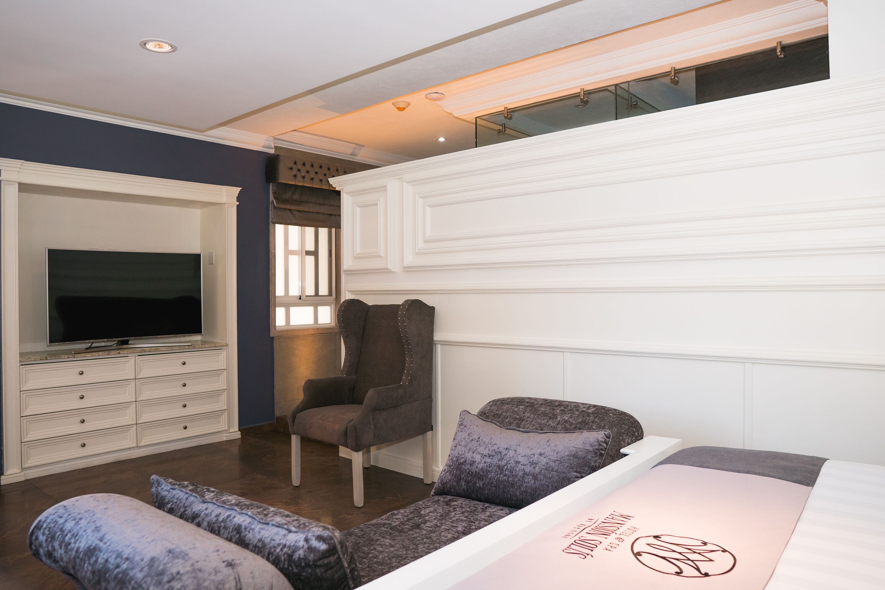 Une chambre à coucher avec un lit, une télévision, une chaise et une fenêtre.