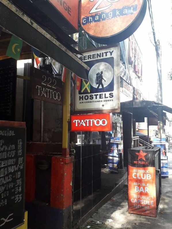 A street view with various signs including a tattoo shop, a hostel, and a Republic Club Bar. - Serenity Hostels (Kuala Lumpur)