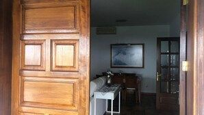 Une porte en bois avec un panneau de verre, une table blanche ornée d’un vase et un tableau encadré accroché au mur.