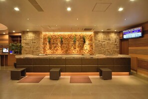 A reception area with a stone wall, a flat-screen TV, and a seating area with cushioned stools.