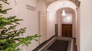 A hallway with a radiator, a wooden door with a coat of arms, and a hanging light fixture. - No.23 Premium Aparthotel (Kraków)