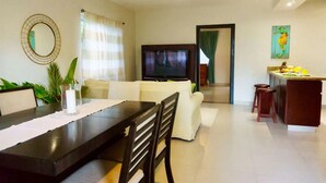 Sala de estar moderna com área de jantar, televisão de tela plana e cozinha com banquetas.