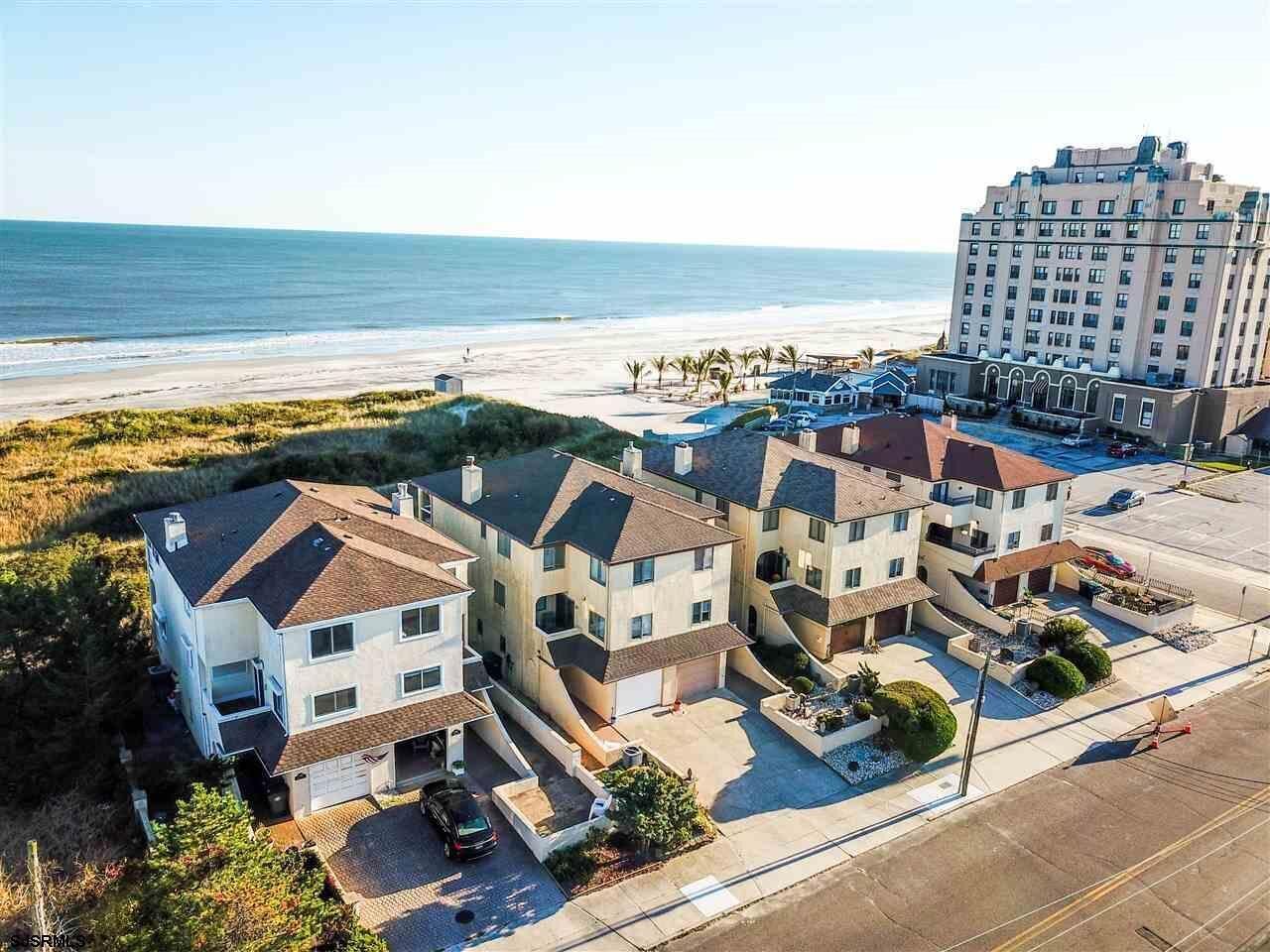 Zona residencial costera con vista a la playa, con casas de varios pisos y un gran edificio de hotel.