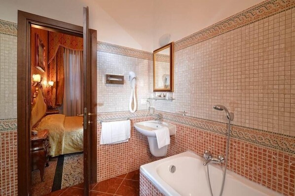 A bathroom with a bathtub, a sink, and a hairdryer. - Residenza San Maurizio (Venice)