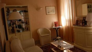 A hotel room with a sofa, armchair, small table, and a cabinet with a mirror. - Hotel Cannaregio 2357 (Venice)
