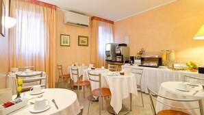 A hotel dining area with round tables, chairs, a coffee machine, and a TV. - Hotel Cannaregio 2357 (Venice)
