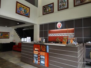 A hotel reception area with a modern design, featuring a reception desk, a staircase, and framed artwork on the walls. - Davao Royal Suites and Residences (Davao)