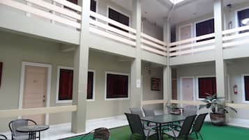 A multi-level indoor space with a central table surrounded by chairs, a green carpet, and a fire extinguisher on the wall.