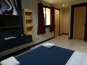 A hotel room with a bed, a TV, a shelf, and a door. - Davao Royal Suites and Residences (Davao)