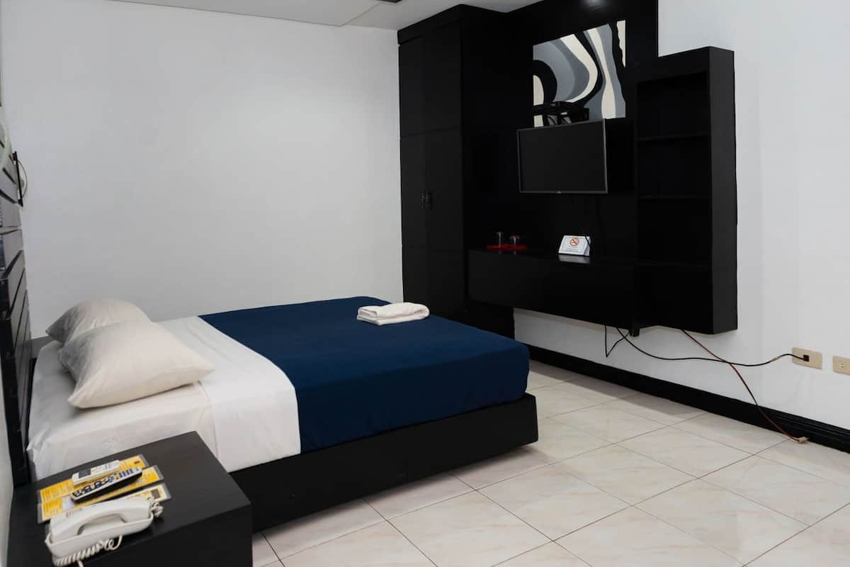 A modern bedroom with a bed, bedside table, and a mounted TV.