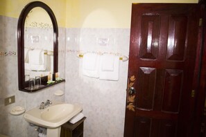 A bathroom with a sink, mirror, and wooden door. - Tierras Enamoradas (San Lorenzo)