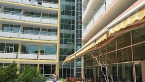 A multi-story hotel with balconies, outdoor seating, and a glass facade. - Grand Hotel Nirvana (Nessebar)