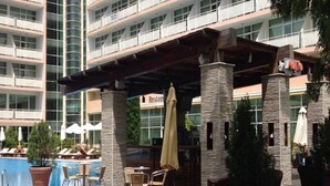 A hotel pool area with outdoor seating, a restaurant, and a view of the building's exterior. - Grand Hotel Nirvana (Nessebar)