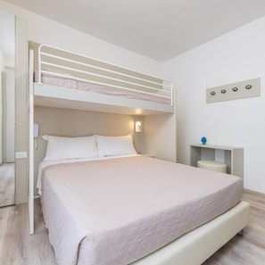 A bunk bed with a desk and chair, a bedside table, and a wall-mounted light fixture. - Hotel Madera (Jesolo)