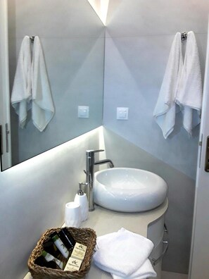 A modern bathroom with a large mirror, a white sink, and two towels hanging on the wall. - Maistros Exclusive Suites (Rethymno)
