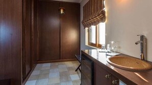 A modern bathroom with a wooden vanity, a round sink, and a hanging light fixture. - Maistros Exclusive Suites (Rethymno)