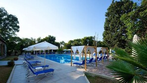 A swimming pool with blue lounge chairs and white umbrellas. - Amalia Corfu Hotel - Adults Only (Corfu)