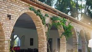 A brick building with arched doorways and a covered walkway. - Amalia Corfu Hotel - Adults Only (Corfu)