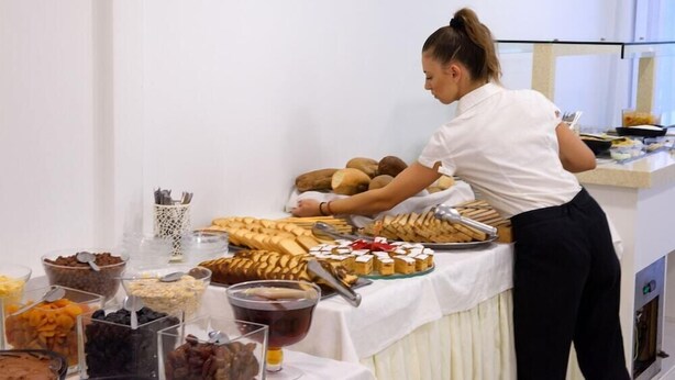 A buffet setup with various food items and a person serving. - Amalia Corfu Hotel - Adults Only (Corfu)