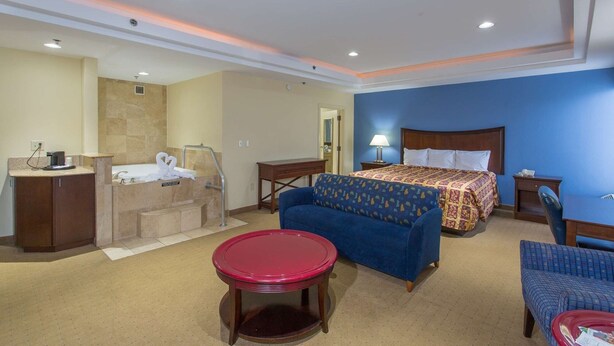 Hotelkamer met een bed, een bureau, een stoel, een klein tafeltje, een bank en een badkamer met een badkuip en handdoekhouder.
