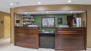Een receptiebalie met een groene muur, een ingelijst kunstwerk en een beveiligingscamera.