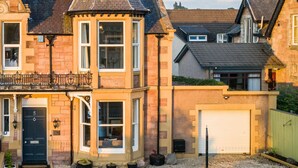 A traditional two-story house with a prominent bay window, a front door labeled '5', and a garage. - West of the Ness • Large City Home • Hot Tub (Inverness)