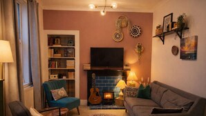 Un salon chaleureux avec une cheminée, une bibliothèque, un téléviseur et des fauteuils confortables.