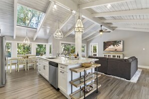 Una cocina amplia con una isla grande, iluminación colgante y vistas al exterior.