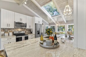 Enjoy cooking in this well-equipped kitchen with a central island, stainless steel appliances, and a skylight.