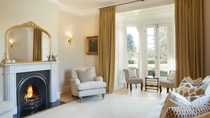 Een woonkamer met een open haard, een bank, een stoel en een tafel.