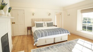 Een slaapkamer met een groot bed, een open haard en een raam met uitzicht.