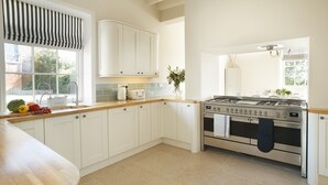 Een keuken met witte kastjes, een fornuis, een spoelbak en een raam met uitzicht op het buitenland.