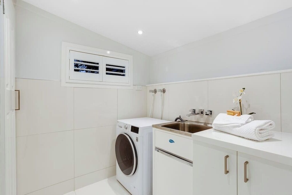 Un bagno moderno con lavatrice integrata, un lavandino e un porta asciugamani.