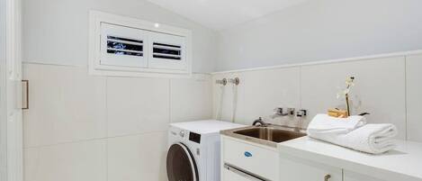 Un bagno moderno con lavatrice integrata, un lavandino e un porta asciugamani.