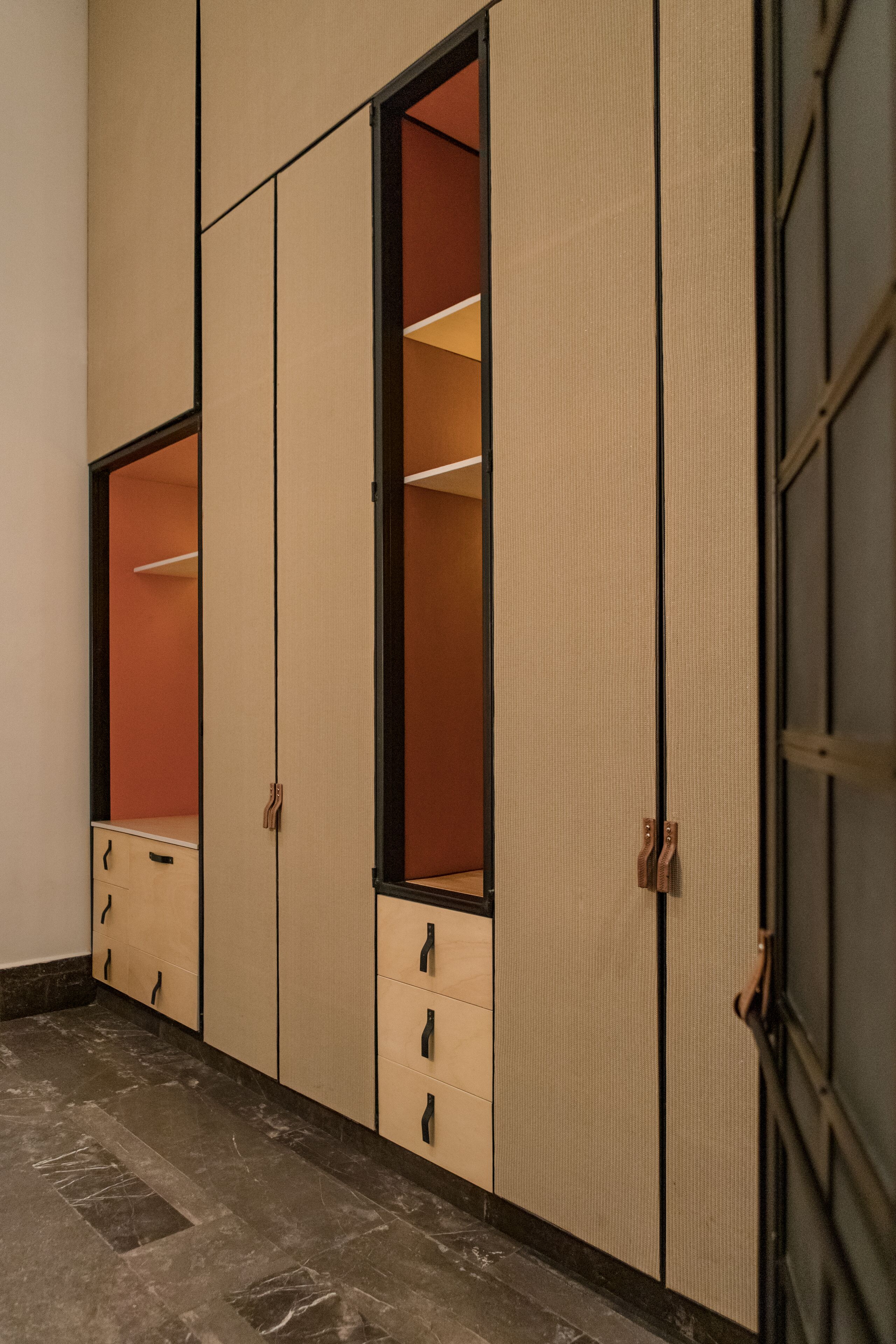 A walk-in closet with sliding doors and a marble floor.