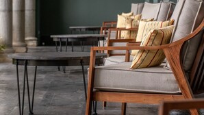 A seating area with a sofa and chairs, a table, and a dark floor. - Antelar Casa Destino (Mérida)