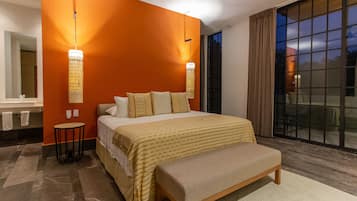 Een moderne slaapkamer met een groot bed, een bankje, een bijzettafeltje en een groot raam met gordijnen.